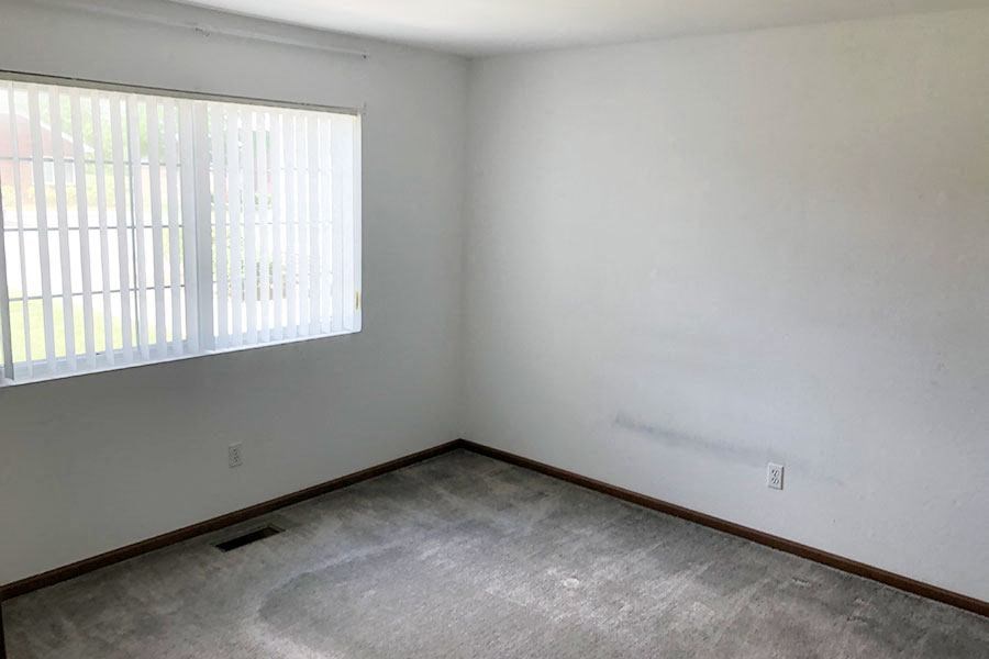 an empty room with a window and a concrete floor