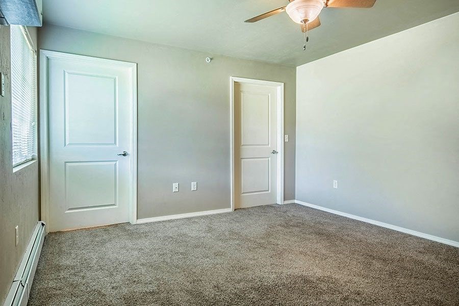 an empty room with white doors and a ceiling fan
