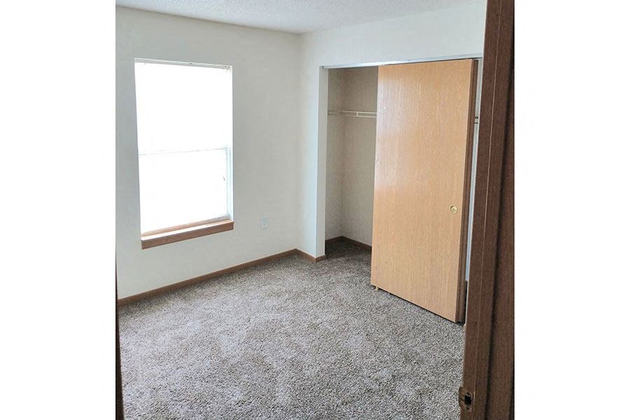 an empty room with a closet and a window