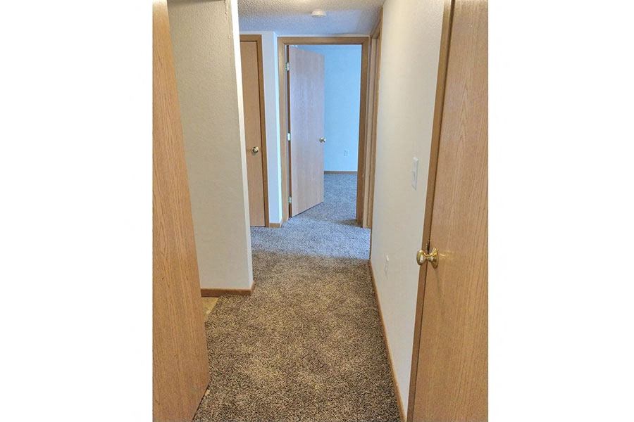 a hallway with an open door and a carpeted floor