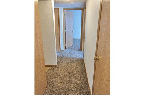 a hallway with an open door and a carpeted floor