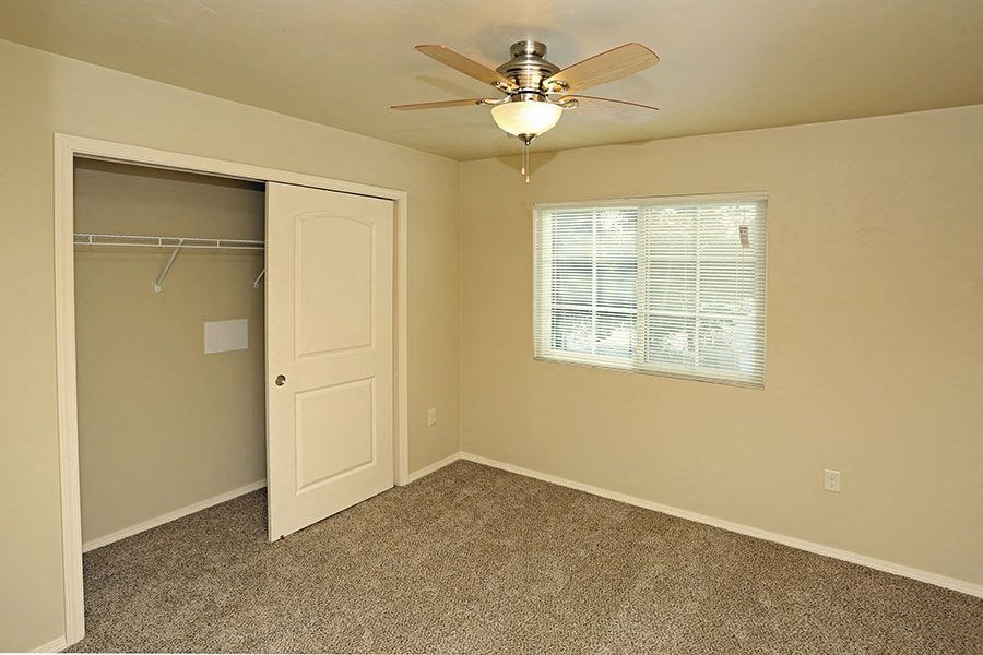 an empty bedroom with a ceiling fan and a closet