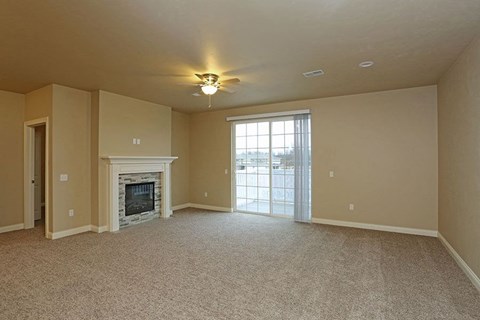 an empty living room with a fireplace and a ceiling fan