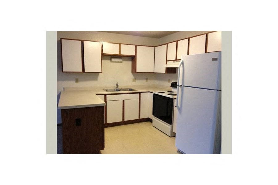 a small kitchen with white cabinets and a refrigerator