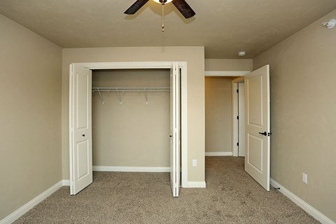 an empty bedroom with a closet and a ceiling fan