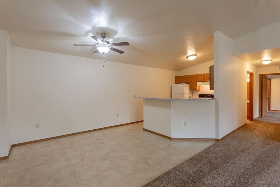a living room with a kitchen and a ceiling fan