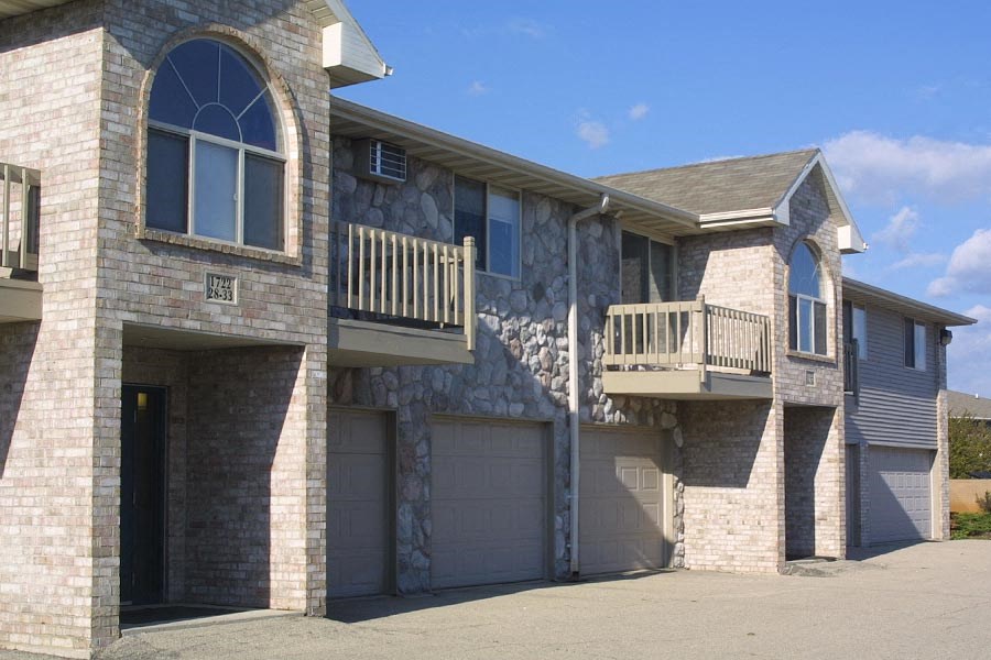 a brick house with a balcony and garage doors