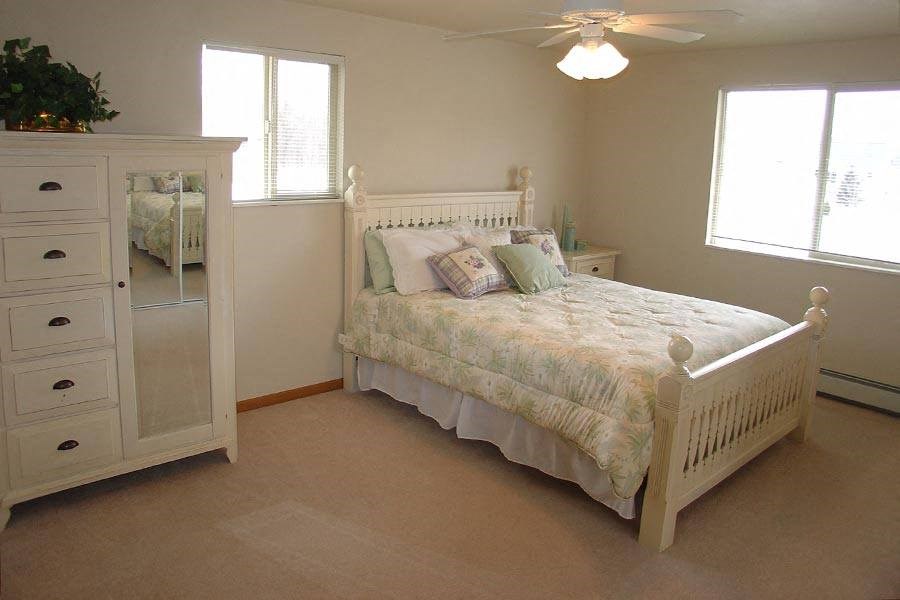 a bedroom with a white bed and a white dresser