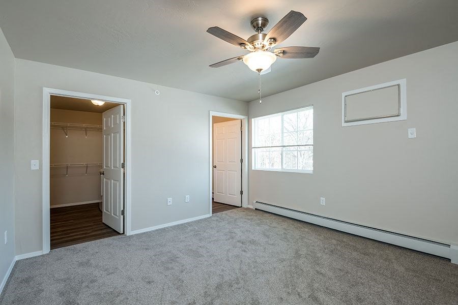 an empty living room with a ceiling fan