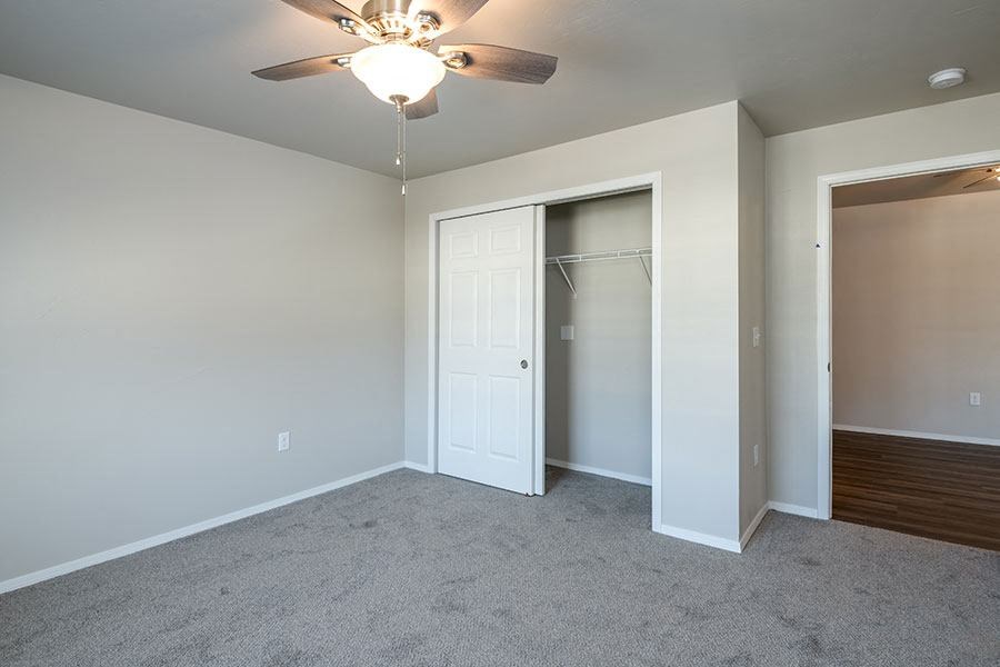 an empty bedroom with a ceiling fan and a closet