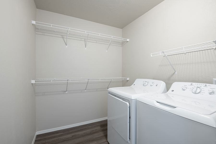 a white laundry room with two washes and a dryer