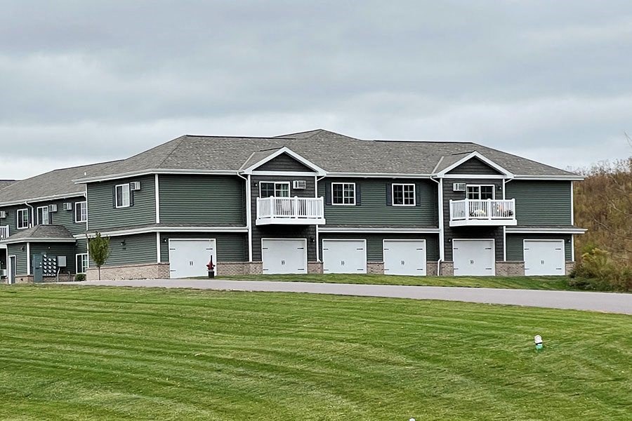 a green house with white garage doors