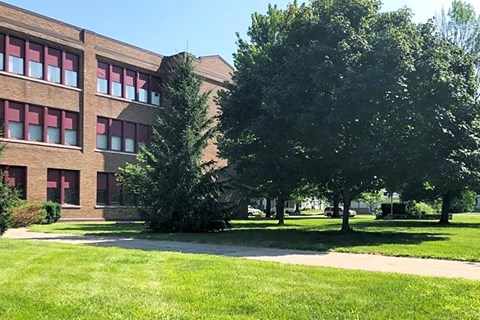 a large brick building with grass and trees in front of it