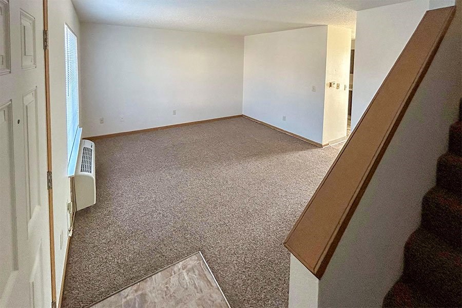 an empty living room with white walls and carpet