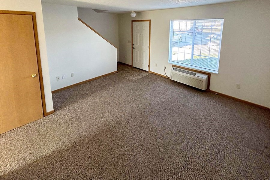 an empty living room with carpet and a window