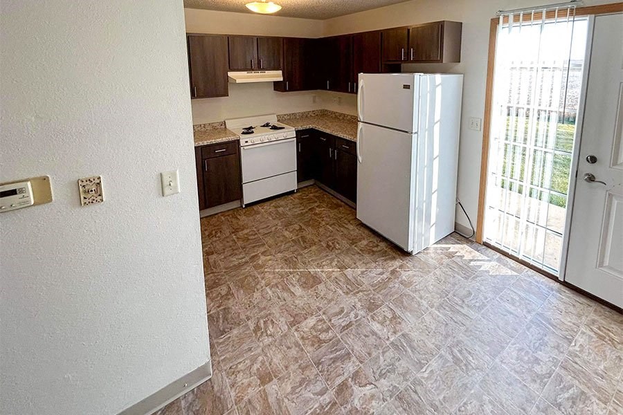 an empty kitchen with a refrigerator and a door