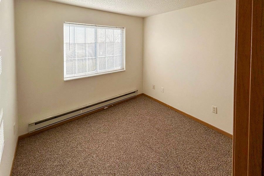 an empty room with a window and carpet