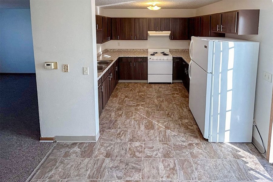 an empty kitchen with a refrigerator and a stove