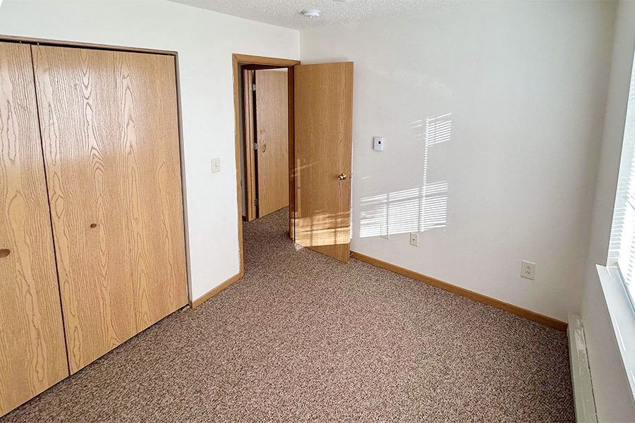 an empty room with two doors and a closet