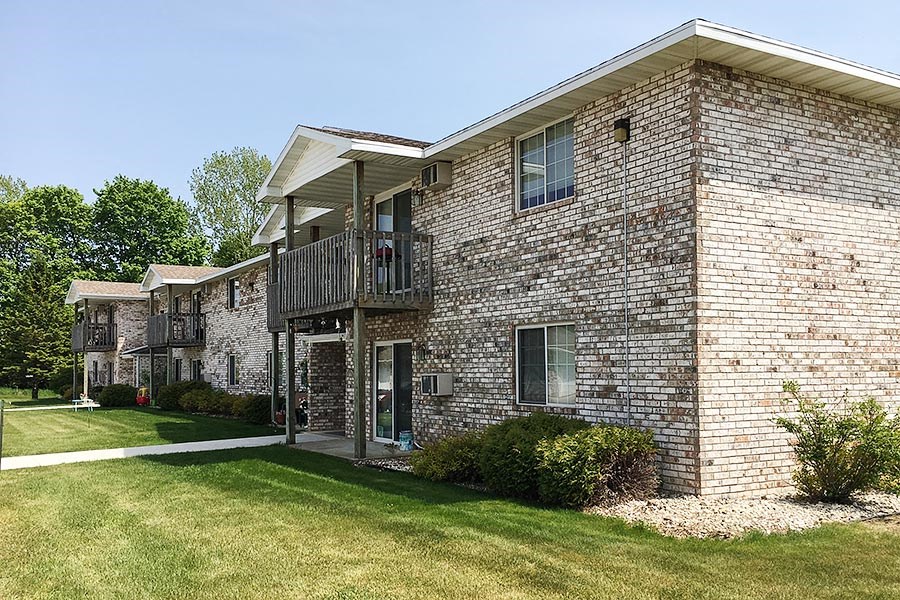 a brick building with a balcony and a lawn