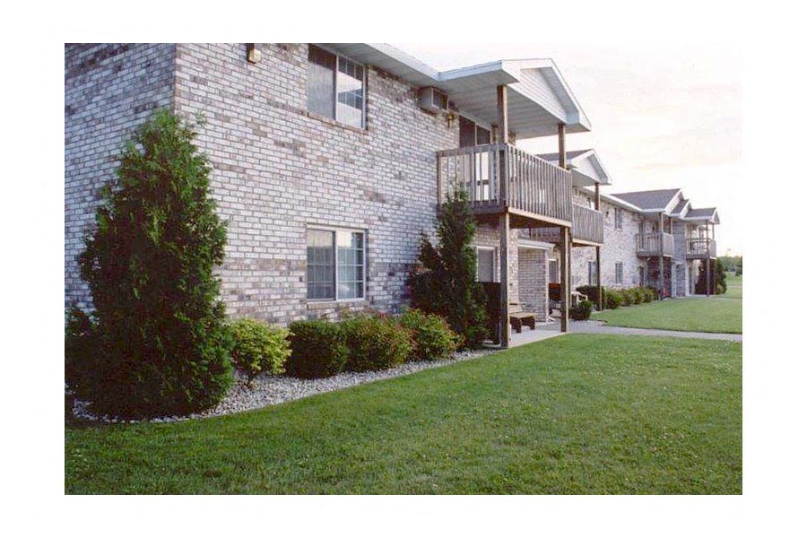 a brick house with a balcony and a lawn