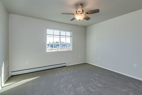 A room with a ceiling fan and a window overlooking a parking lot.
