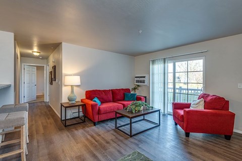 A living room with a red couch and a wooden floor.
