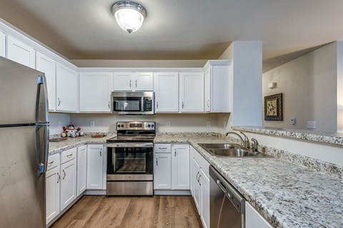A kitchen with white cabinets and granite countertops.