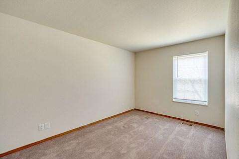 A room with a window and carpeted floor.