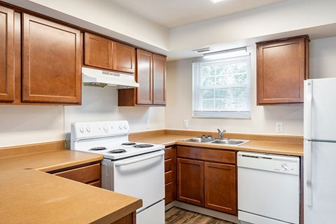 A kitchen with white appliances and wooden cabinets.