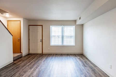 A room with wooden floors and a window with blinds.