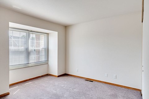 A room with a window and carpeted floor.