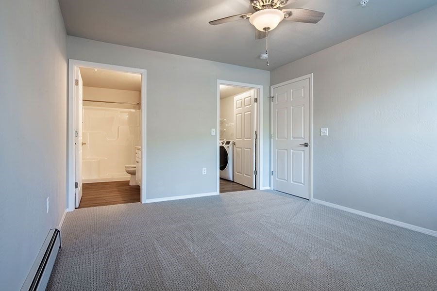 A room with a carpeted floor and a ceiling fan.