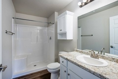 A white bathroom with a sink, toilet, and shower.