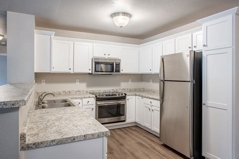 A kitchen with white cabinets and a granite countertop.