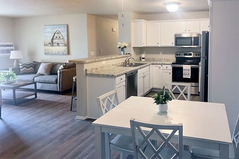 A kitchen with a table and chairs in the foreground and a couch in the background.