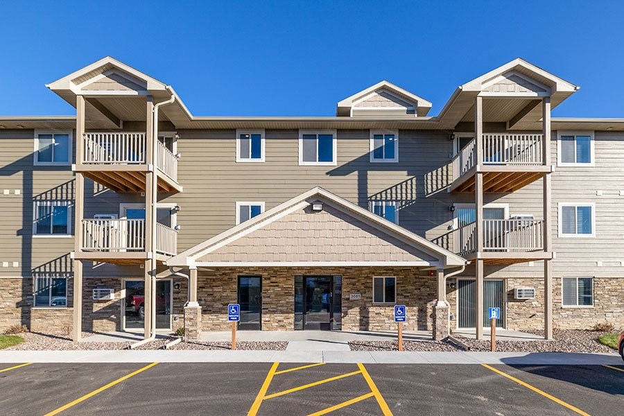A large apartment complex with a parking lot in front.
