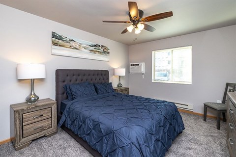 A bedroom with a bed, nightstand, and a ceiling fan.
