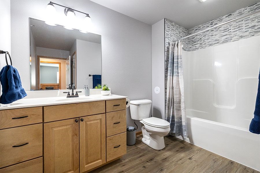 A bathroom with a toilet, sink, and mirror.
