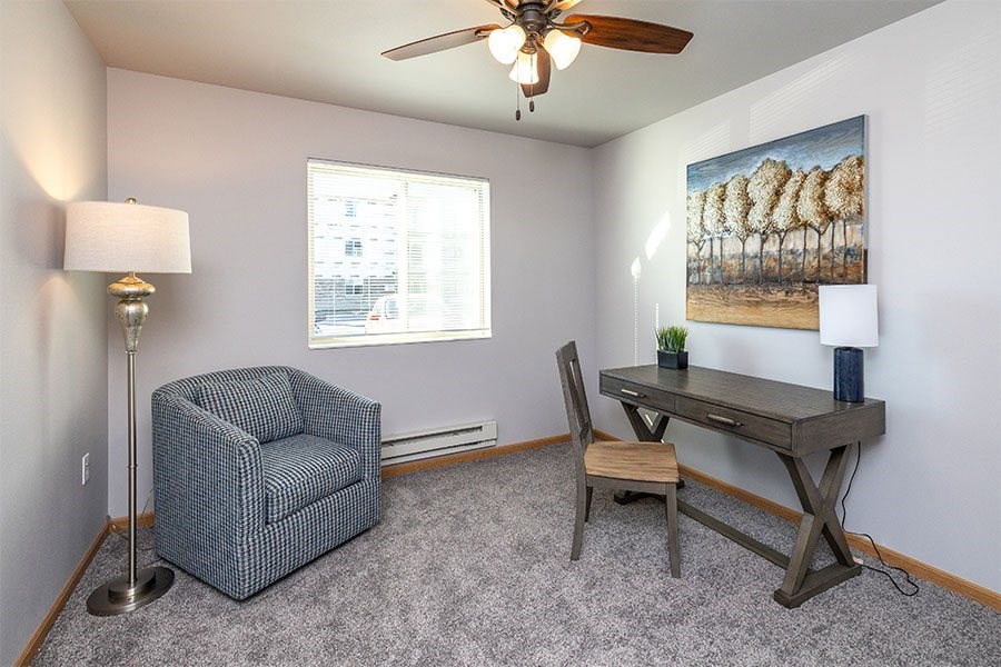 A room with a chair, a desk, and a painting on the wall.