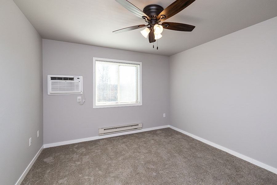 A room with a ceiling fan and a window.