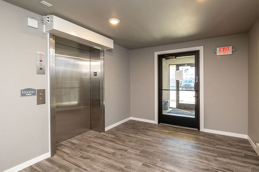 A room with a stainless steel elevator and a door with a glass window.
