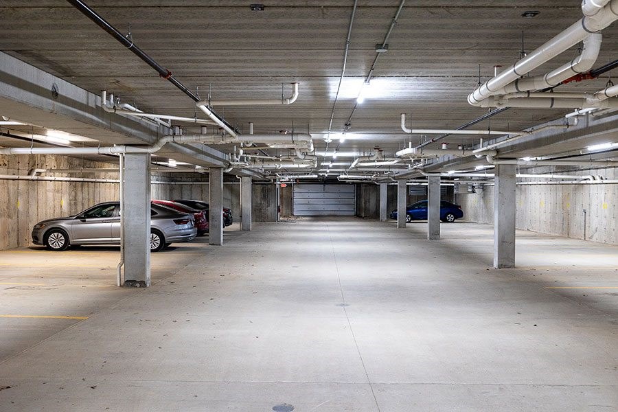 A parking garage with a few cars and a lot of pipes.
