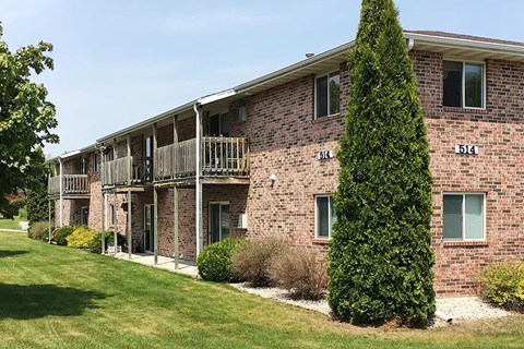 a brick apartment building with balconies and a tree