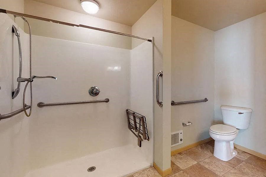 a white bathroom with a toilet and a shower