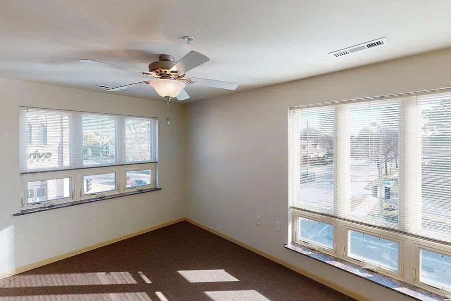 an empty room with a ceiling fan and windows