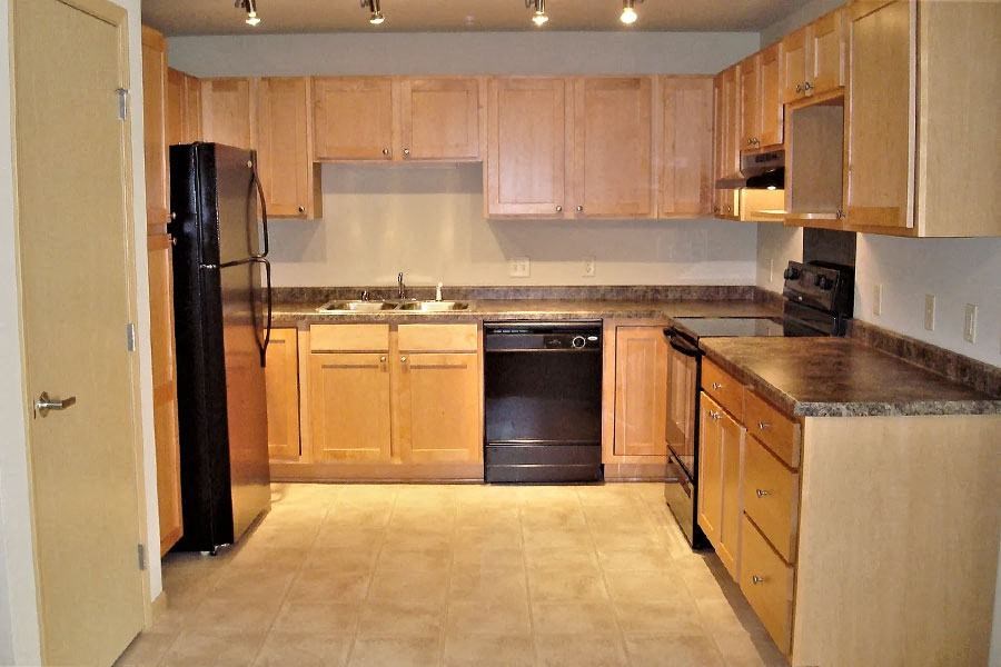 a kitchen with wooden cabinets and a black refrigerator