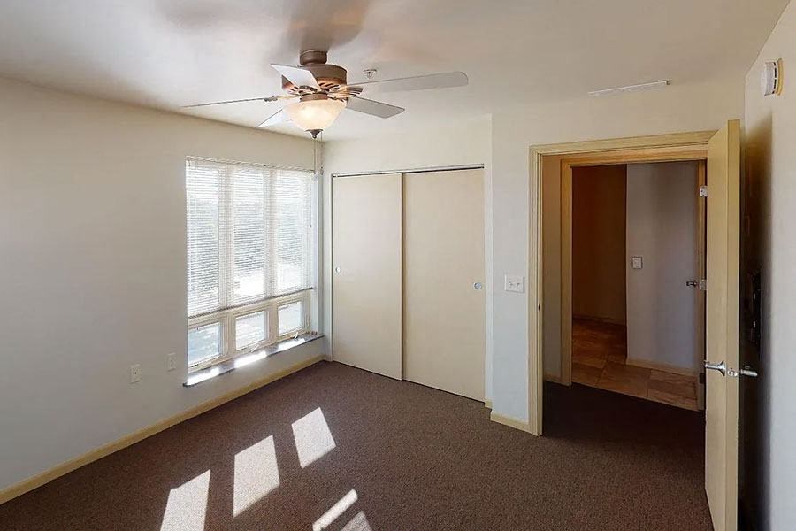 an empty room with a ceiling fan and a window