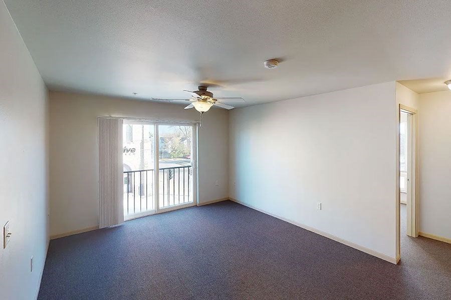 an empty living room with a ceiling fan