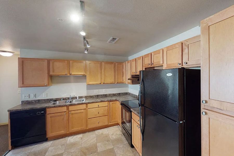 a kitchen with wooden cabinets and a black refrigerator